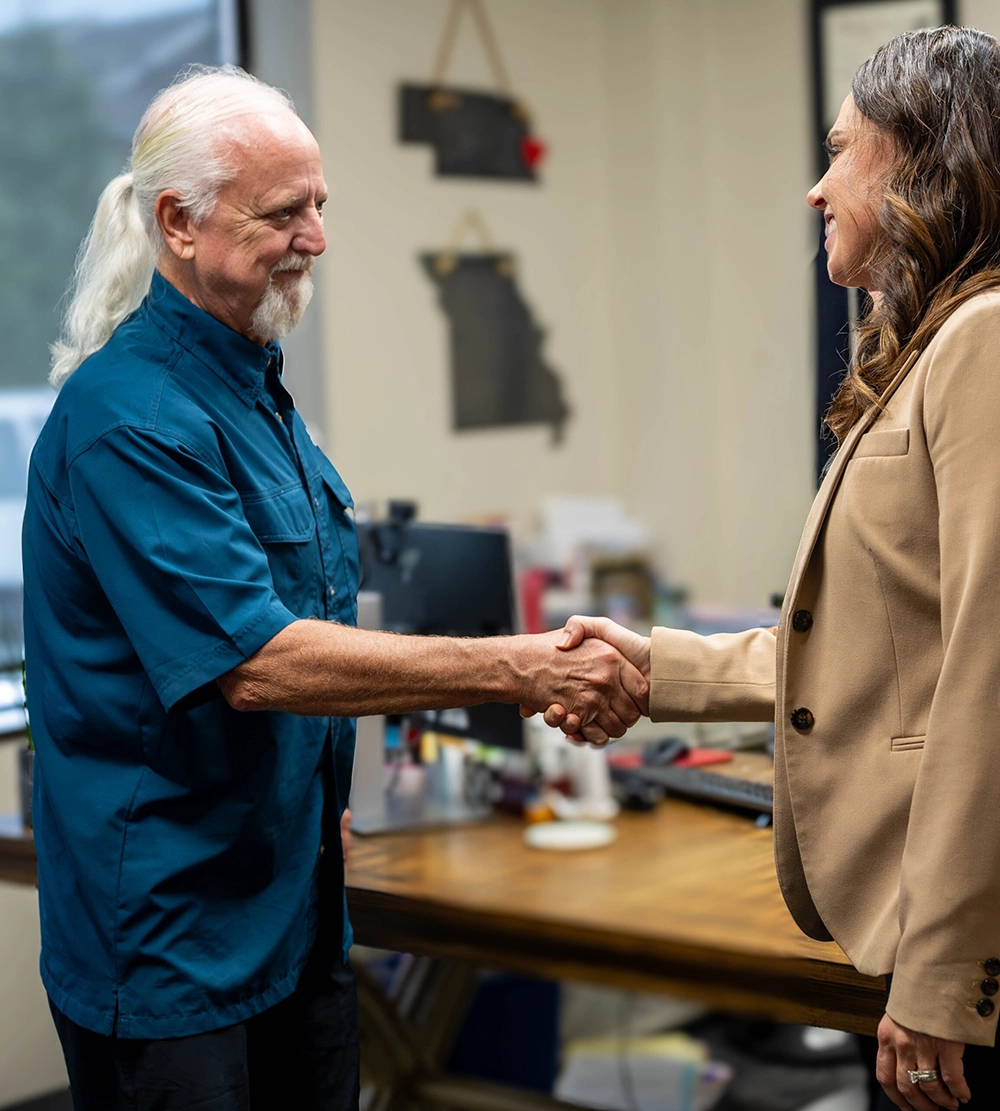 A Fisher Law LLC attorney shaking hands with a client in a professional office setting, symbolizing trust, empowerment, and compassionate family law representation.