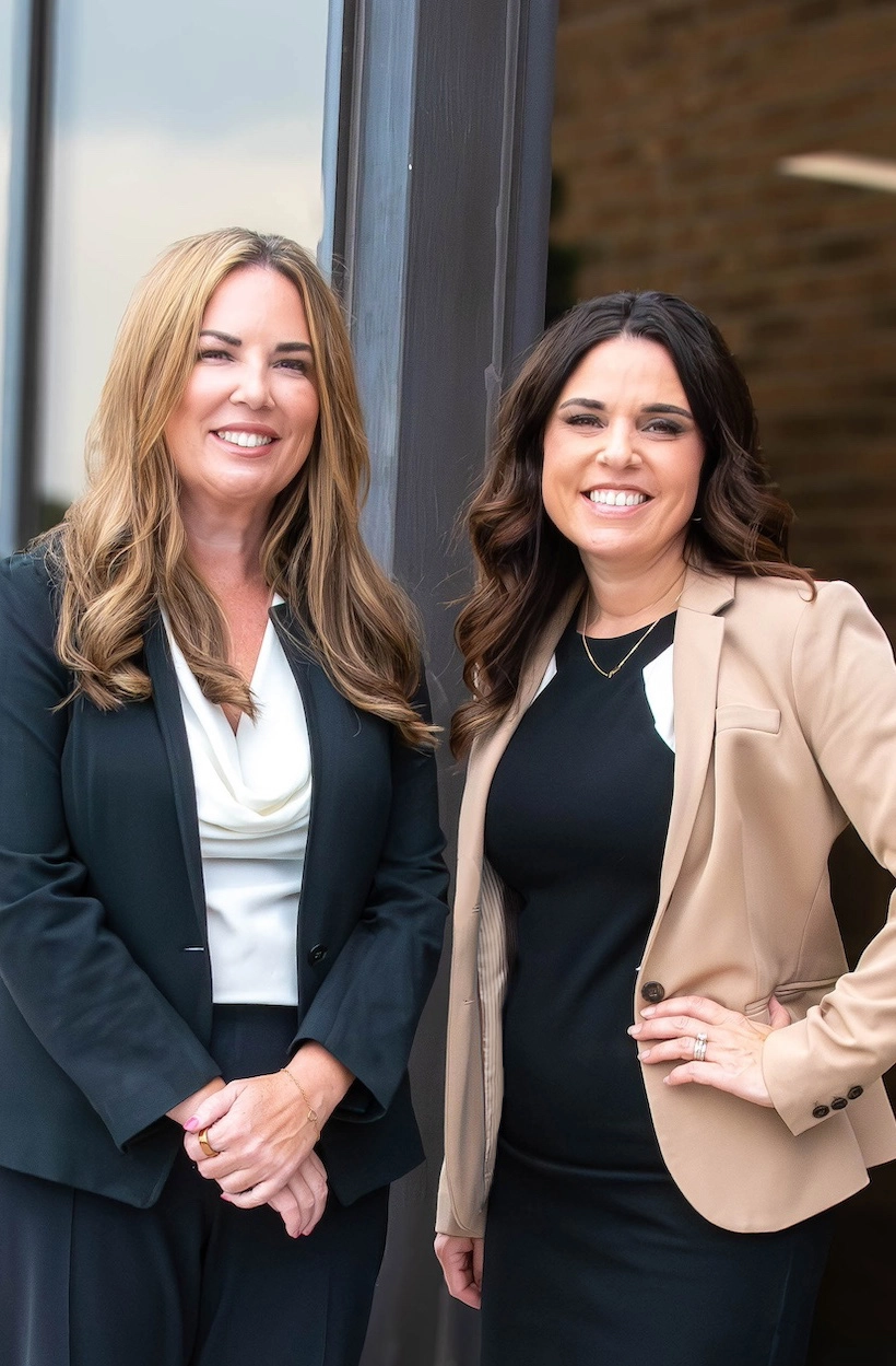 Nicole Fisher and Stacey Wullschleger, founding attorneys of Fisher Law LLC, standing together outside their office, representing a women-led family law firm focused on advocacy and family well-being.